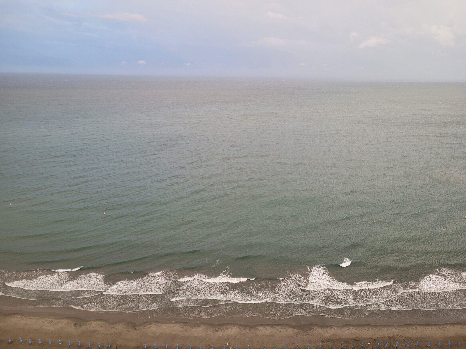 Serene beach at dawn, with gentle waves lapping at the shore and the sky painted in soft hues of blue, reflecting on the water