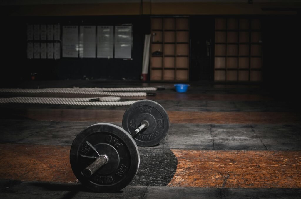 A lone barbell rests in an empty, dimly lit gym, emphasizing strength and solitude.